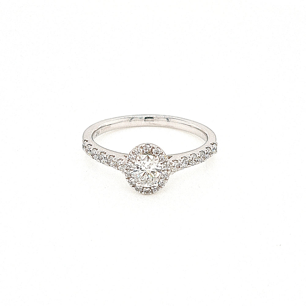 Oval diamond engagement ring. An oval cut diamond in a four claw setting, surrounded by a halo cluster of of micro claw set brilliant-cut diamonds with micro claw set diamond shoulders. 18ct white gold