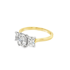 View from the front side of Three stone radiant cut lab grown diamond ring. The larger centre is set with four double eagle claw and the smaller sides are set with four eagle claws. The ring features a plain and tapered yellow shank and the setting is in platinum