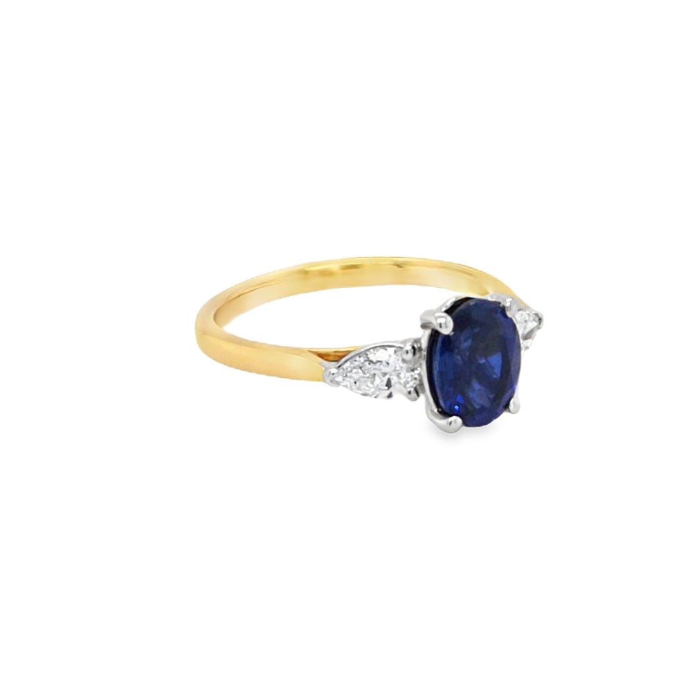 Side view of 18ct gold and platinum lab grown sapphire and diamond ring showing four-claw sapphire mount and three-claw pear diamond settings.