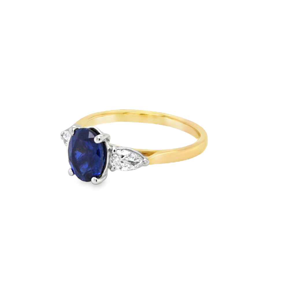 Side view of 18ct gold and platinum lab grown sapphire and diamond ring showing four-claw sapphire mount and three-claw pear diamond settings.