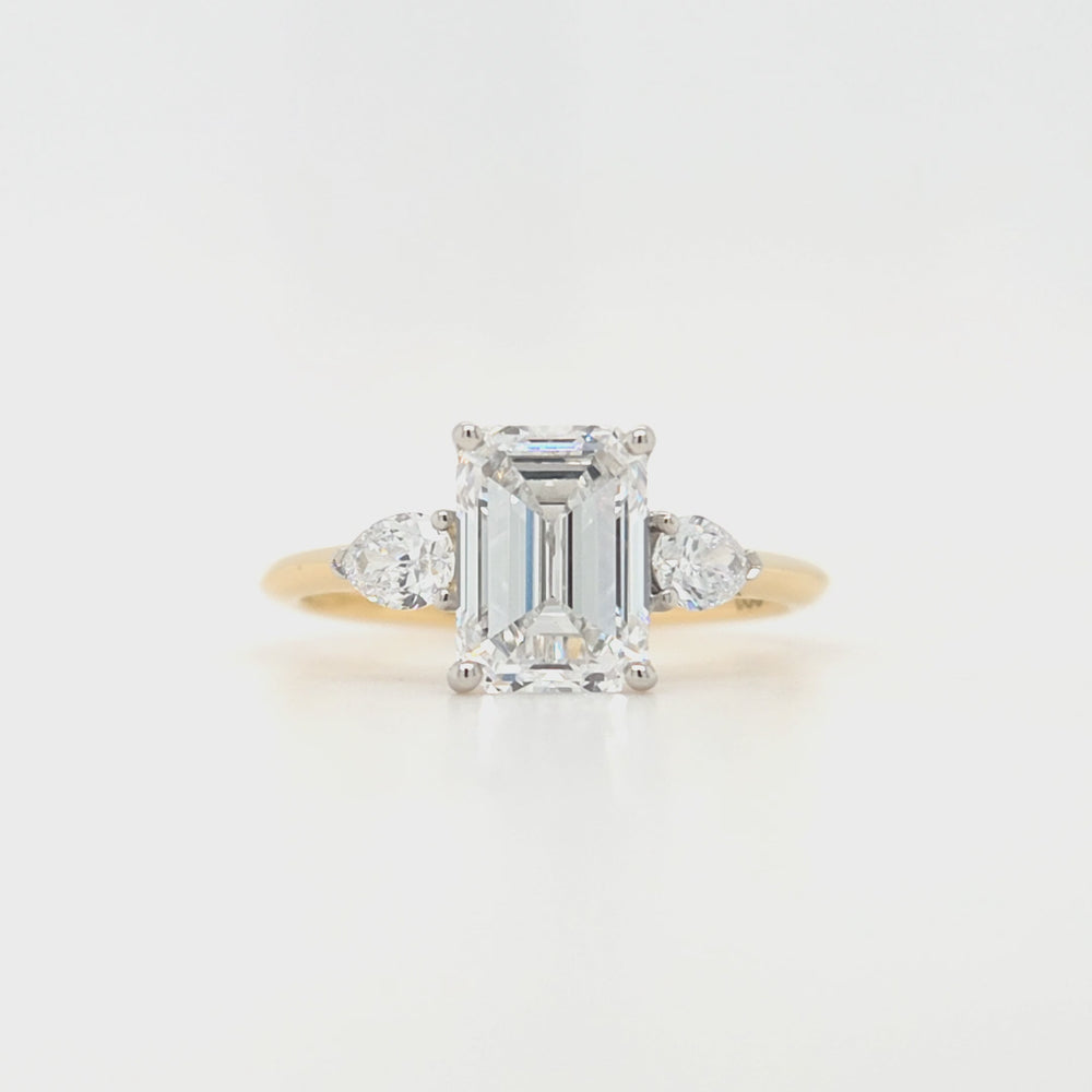 
                
                    Load and play video in Gallery viewer, An emerald-cut and two brilliant-cut lab grown diamonds all in a platinum claw setting with a yellow gold shank
                
            