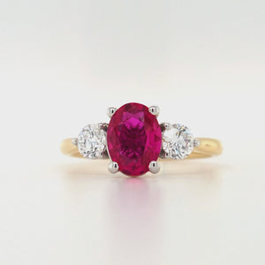 
                
                    Load and play video in Gallery viewer, 18ct yellow gold and platinum three-stone ring featuring an oval lab grown ruby with round brilliant lab diamond sides on white background.
                
            
