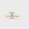 Oval diamond in a four claw platinum setting with a slim yellow gold band and hidden halo