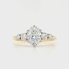 An oval lab grown diamond in a six claw platinum setting with graduating claw set brilliant-cut shoulders and continuing to a yellow gold shank.