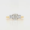 oval and round three stone diamond ring in a platinum setting with a yellow gold band on a white background